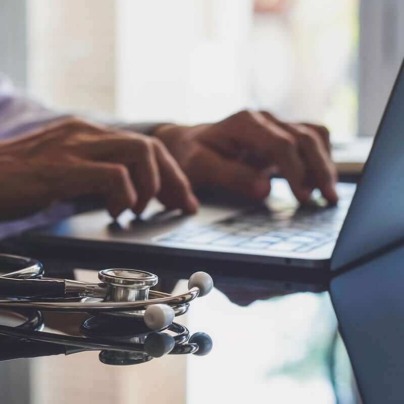 Doctor typing on laptop.